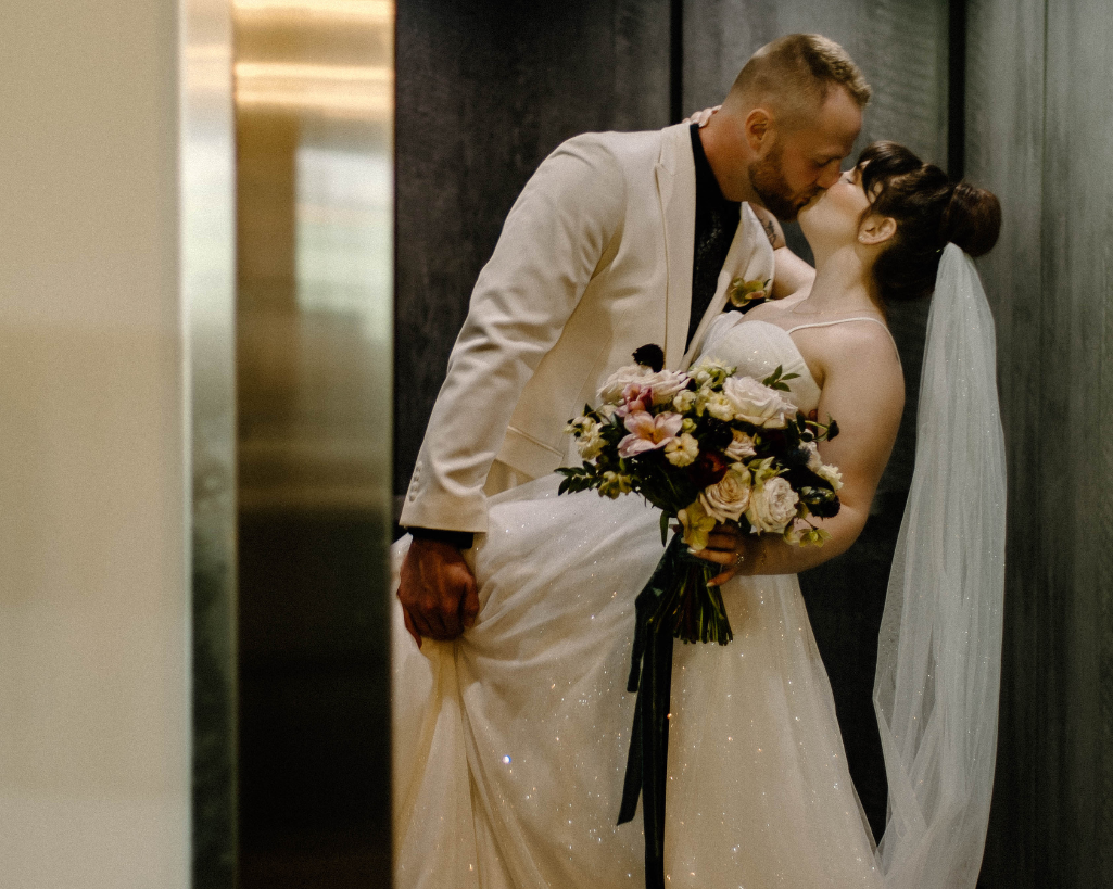 Bride and groom kiss while the elevator door closes