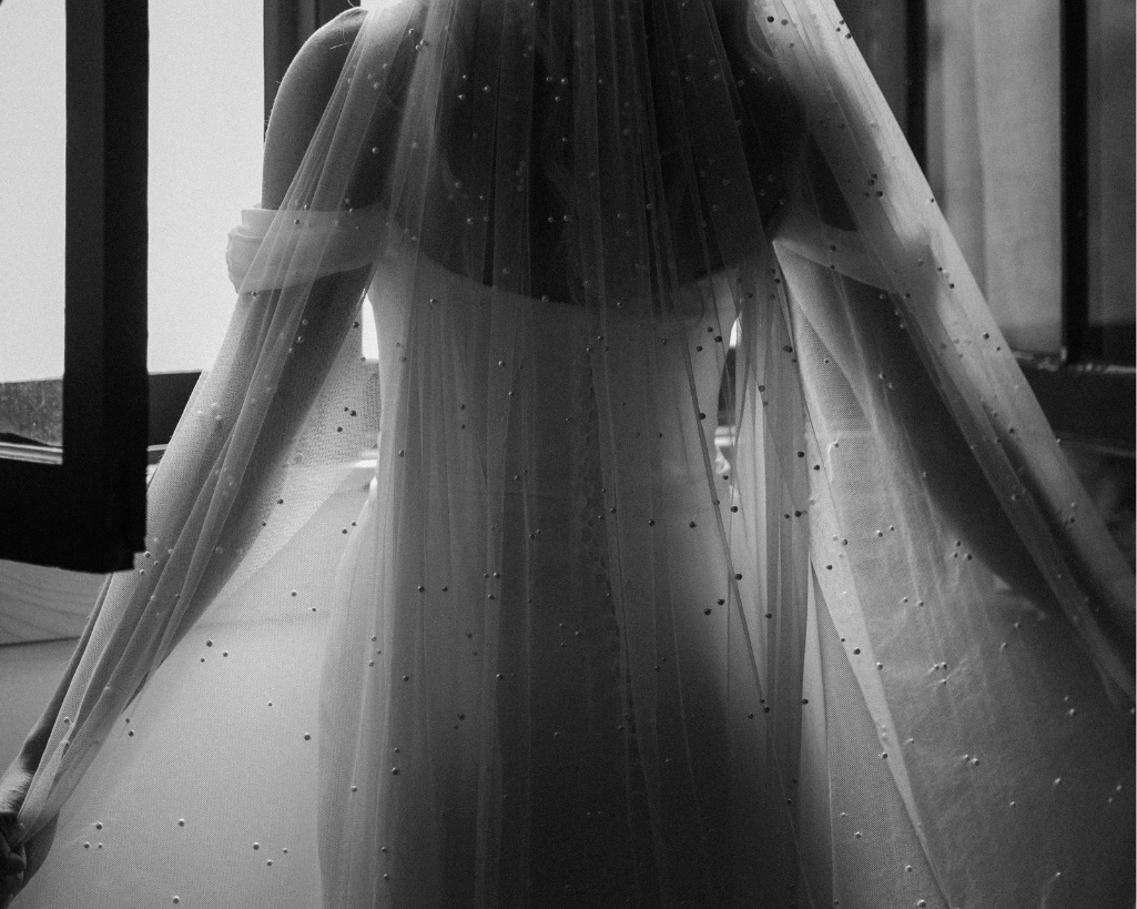 Bride's holds her veil open as the light comes through the cabin window.