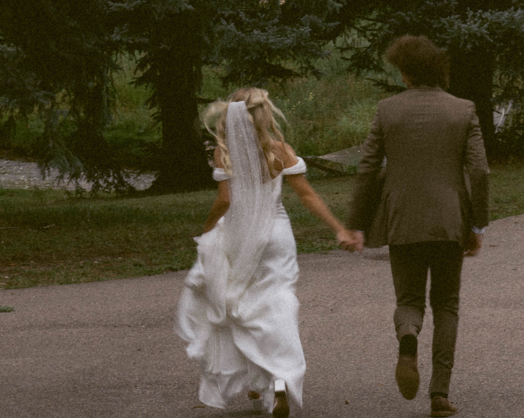 Bride and groom run joyfully near Colorado evergreens.
