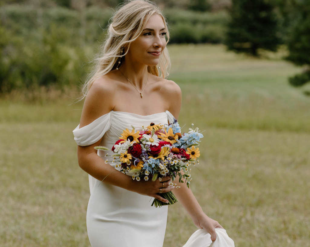 Beautiful bride walking holding wildflower bouquet.