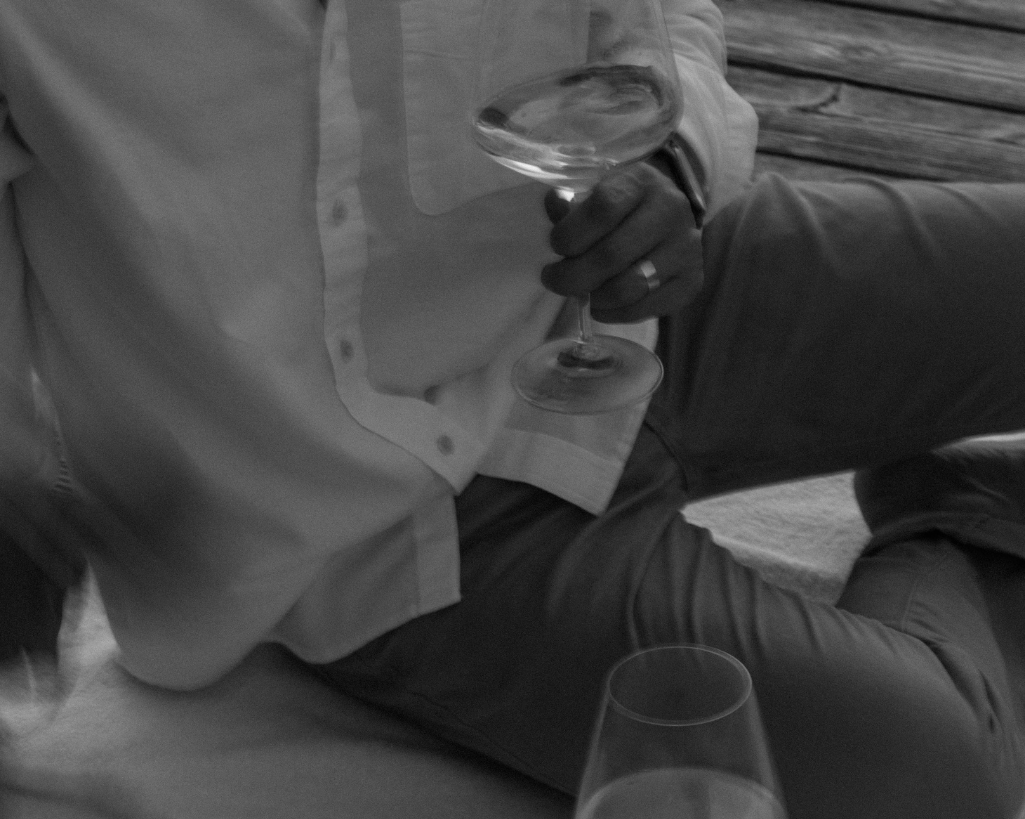 Husband holds wine glass while sitting casually