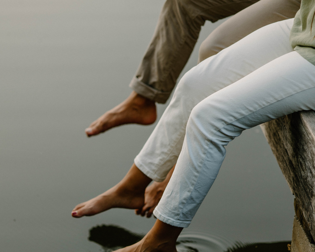 Couple hang their feet into a pond