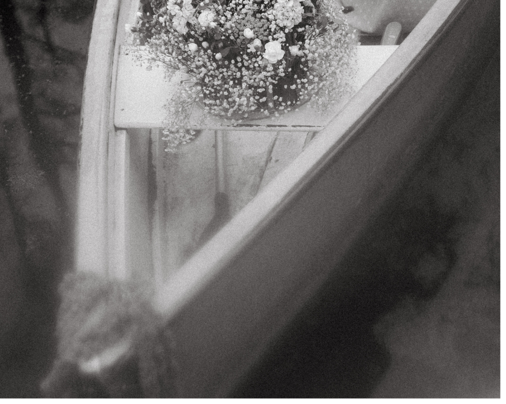 Black and white, film-grain photograph of boat and flowers in South Carolina destination wedding