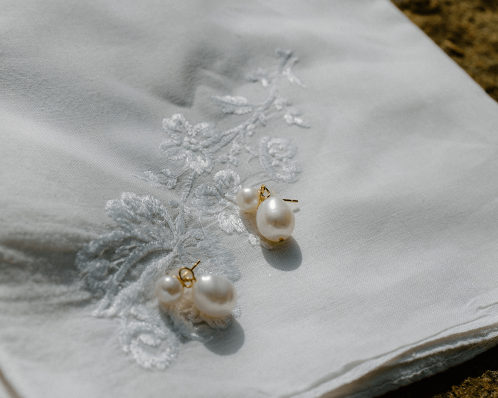 Bride's pearl earrings sit nestled in embroidered handkerchief