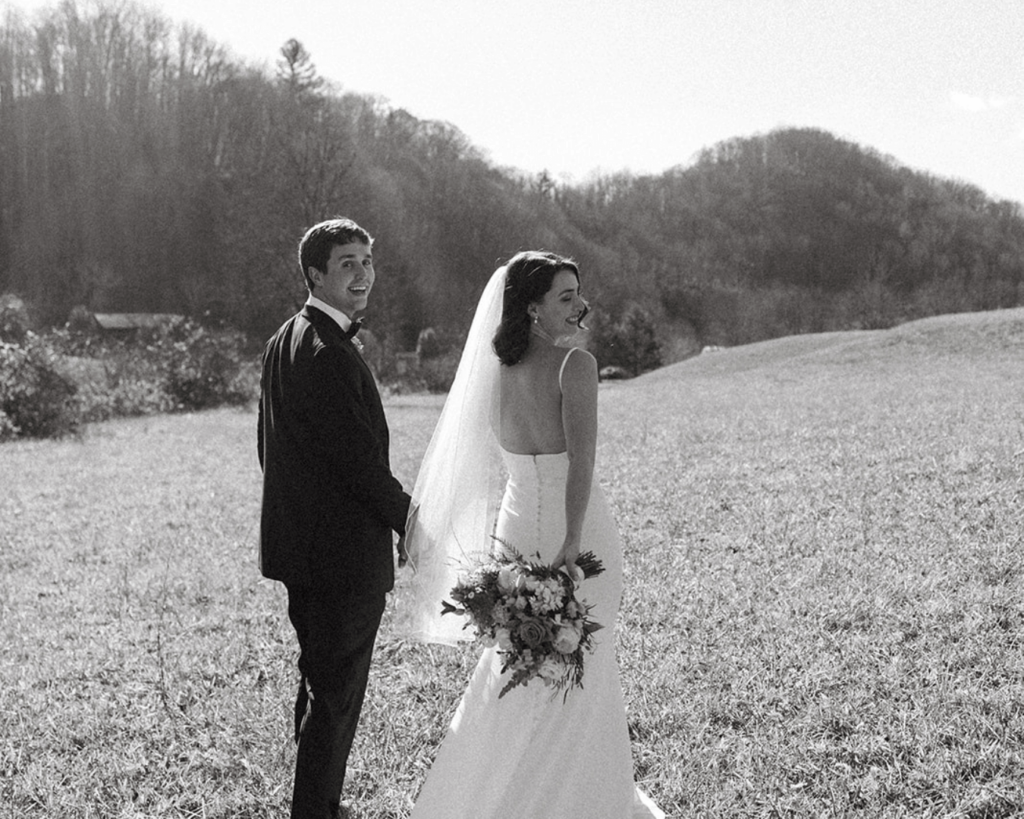Bride and groom carefree in open meadow lined up the Blue Ridge Mountains in North Carolina