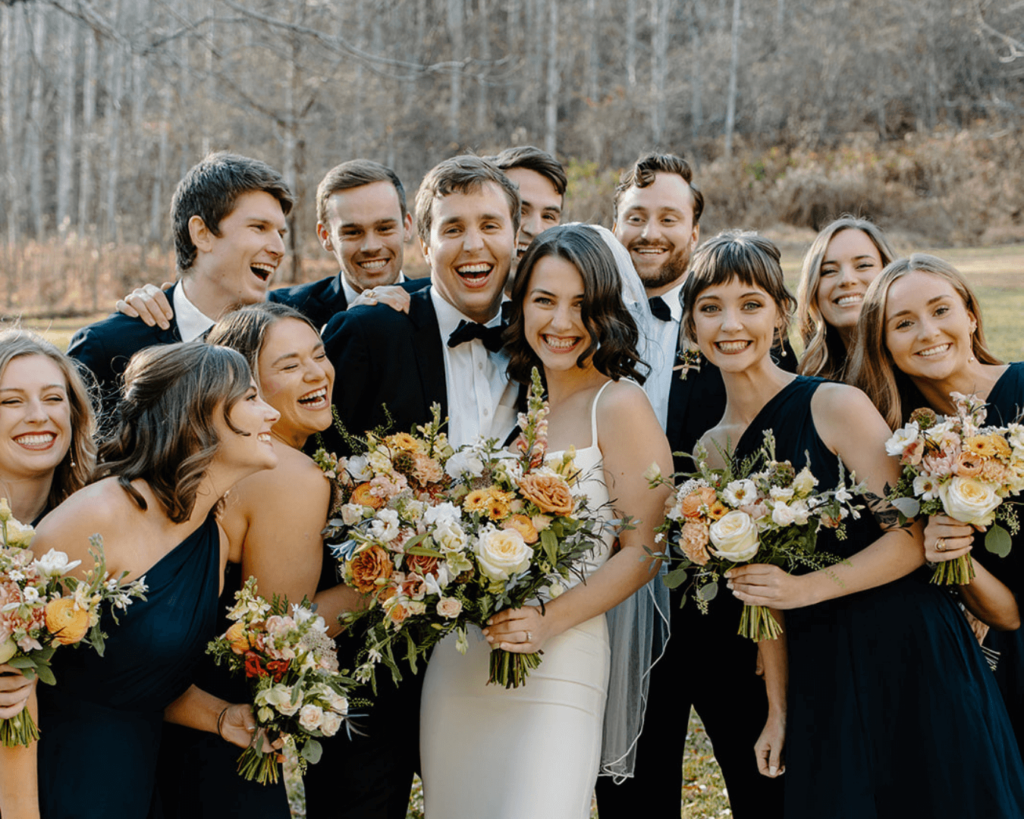 Bride and groom surrounded by wedding party dressed in navy blues in Blue Ridge Mountains.