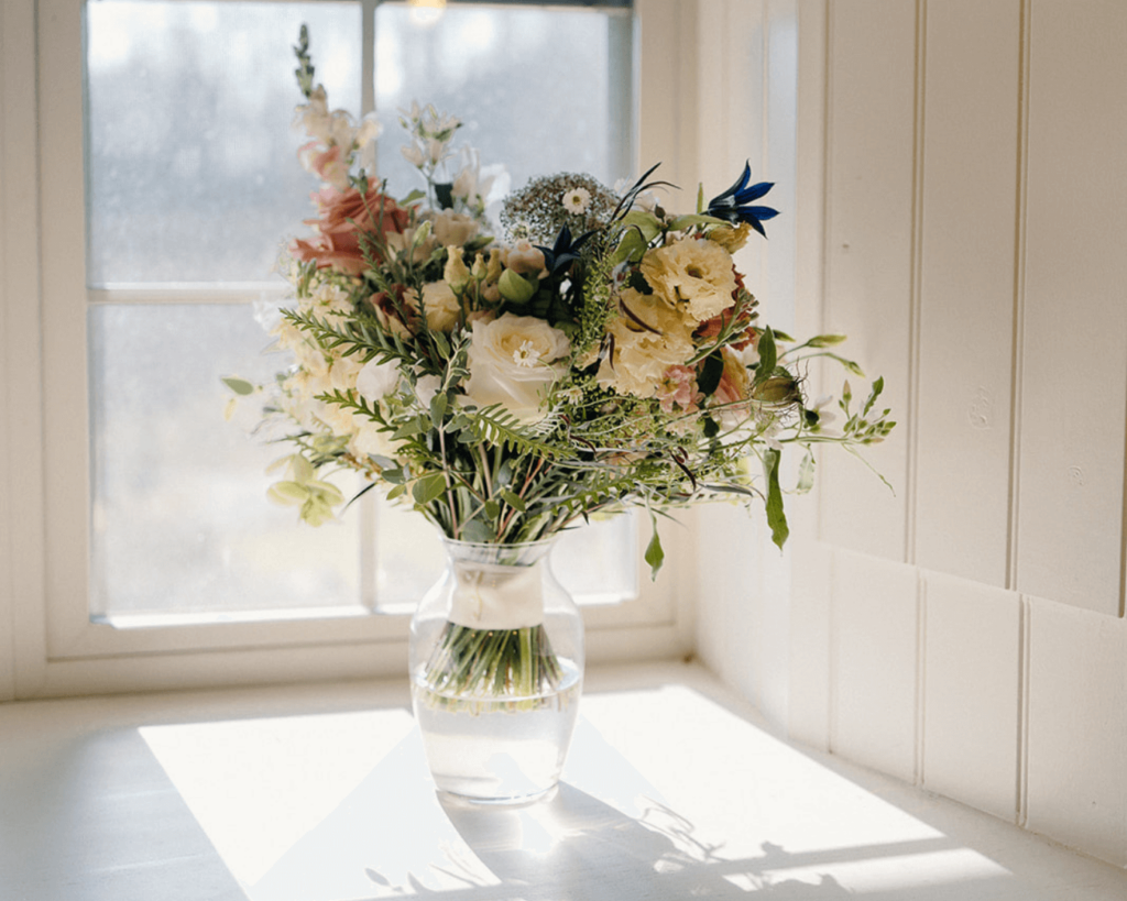 Bridal bouquet in glass vase in sunlit window
