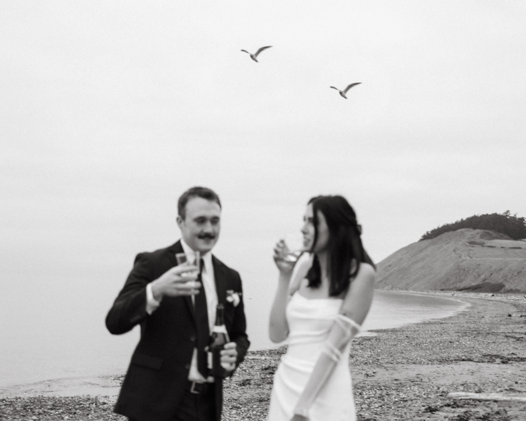 Bride and groom toast on Washington beach in kitschy anti-bride elopement