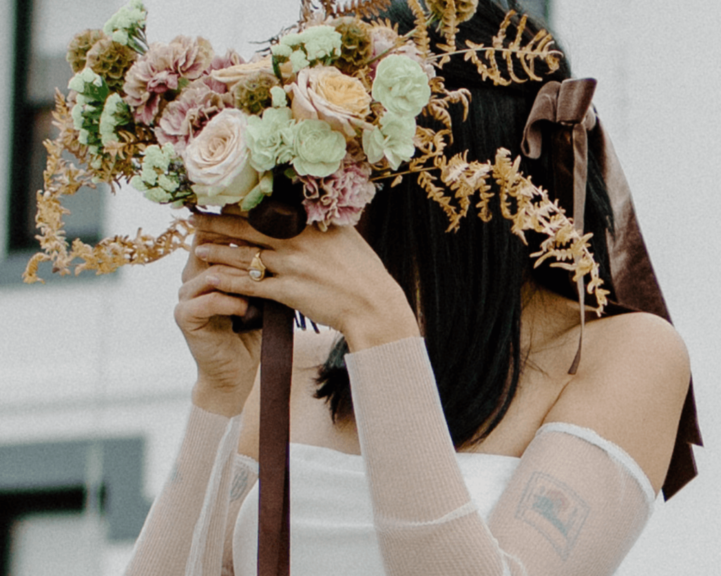 Bride hides her face with warm florals in anti-bride elopement