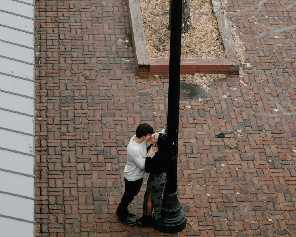 Couple embraces on cobblestone streets with lampposts