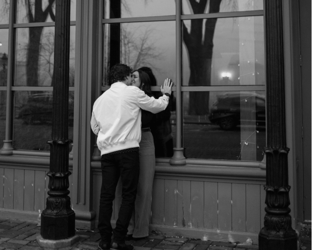 Black and white photo of couple kissing against the Aster Cafe in downtown Minneapolis