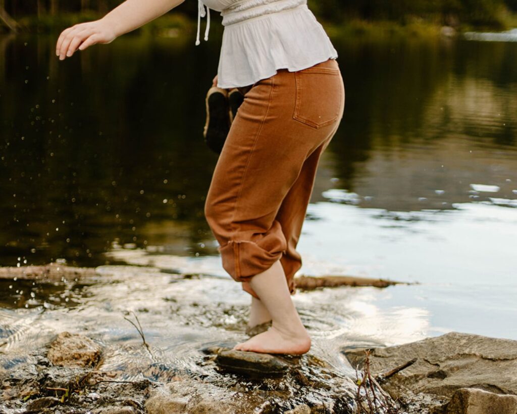 Woman balances on rocks near Colorado creek while exploring