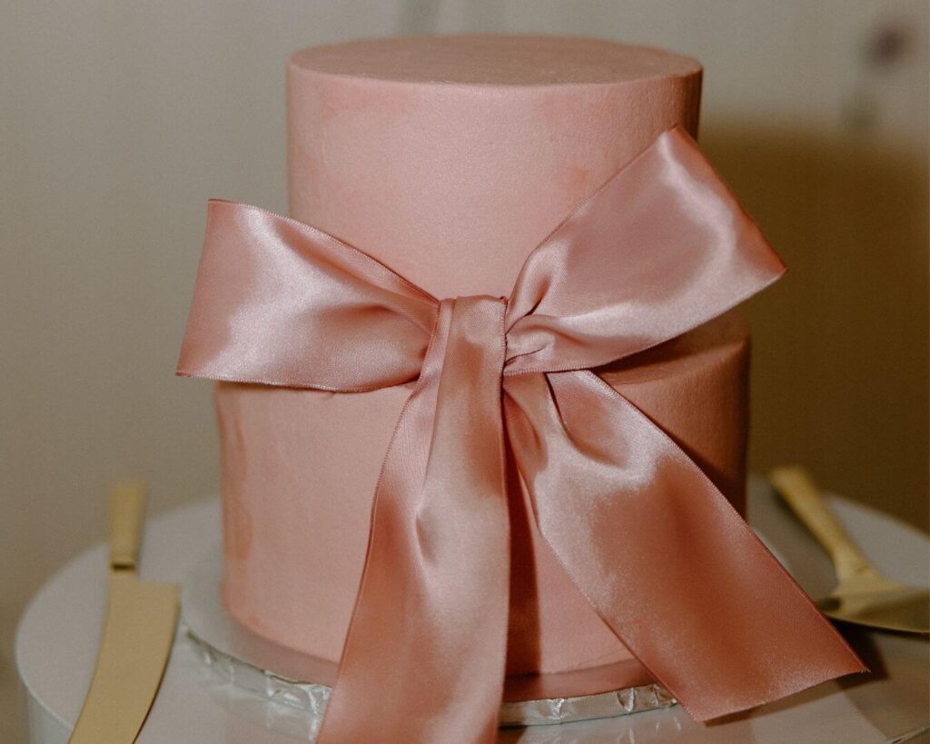 Spring wedding ideas pastel pink cake with bow detail.