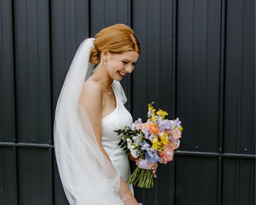 Blushing bride glows as she makes her way down the aisle while holding beautiful pastel bridal bouquet.