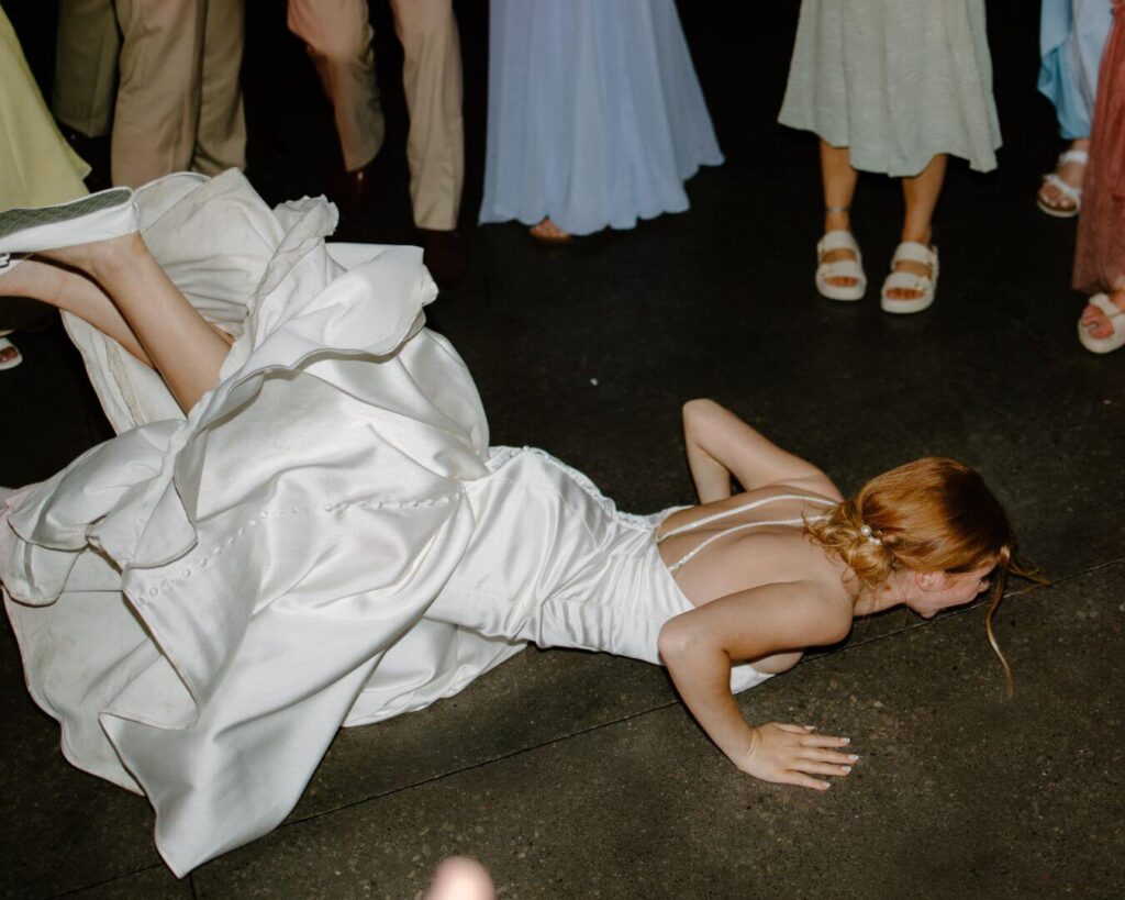 Bride does the worm dance move on the floor of the wedding reception in spring wedding.