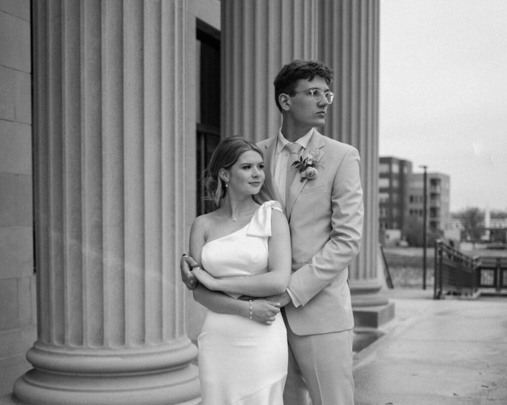 Black and white photo of bride and groom looking off into the distance as they pose in front of the courthouse.