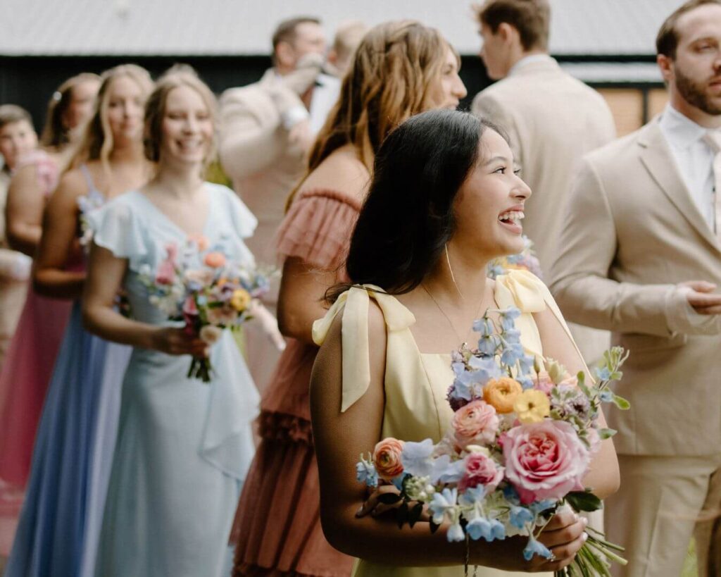 Bridesmaid grins in pastel yellow bridesmaid dress during spring wedding.