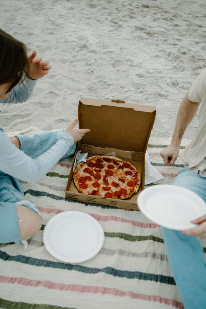Detail photo of couple eating pizza on the beach