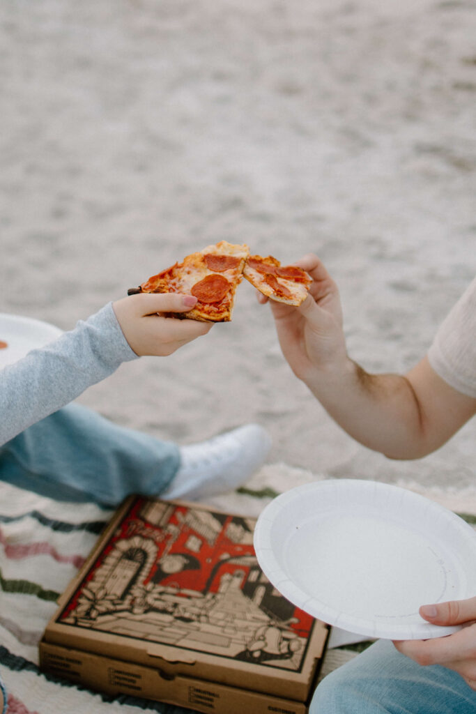 Couple does a 'cheers' with pizza slices in date night photoshoot.