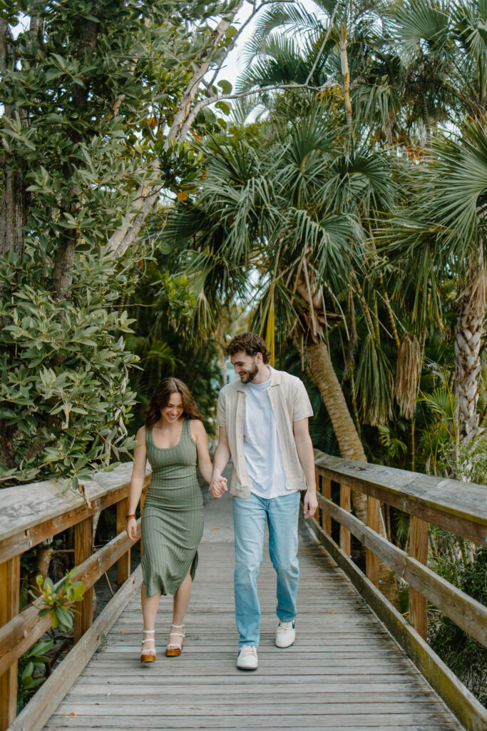 Couple walks across rustic secret bridge in Florida engagement photoshoot