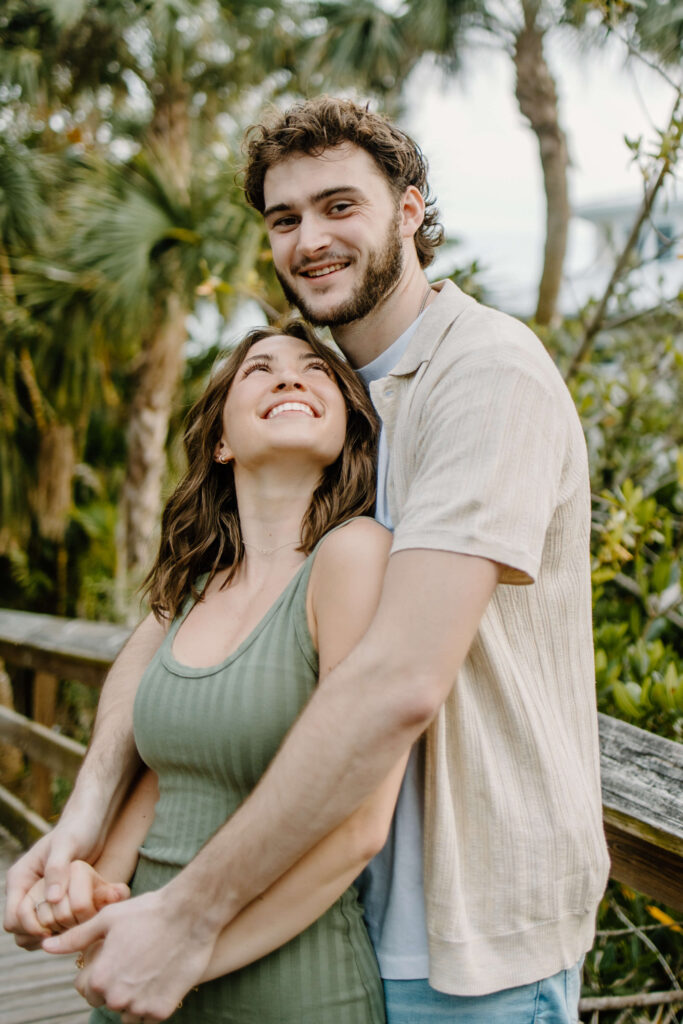 Woman looks up at fiance adoringly while they both smile at the camera