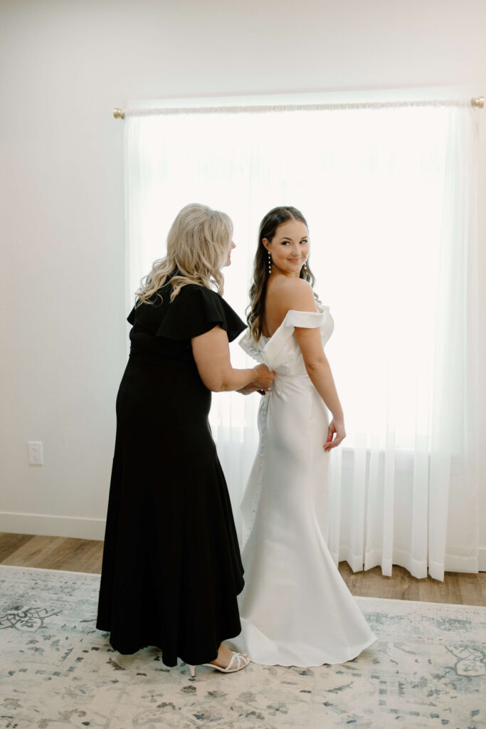 Mother of the bride buttons up bride's gown