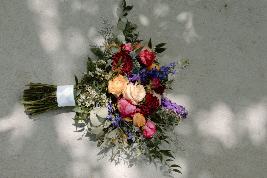 Bride's bouquet lays on concrete in sunlight