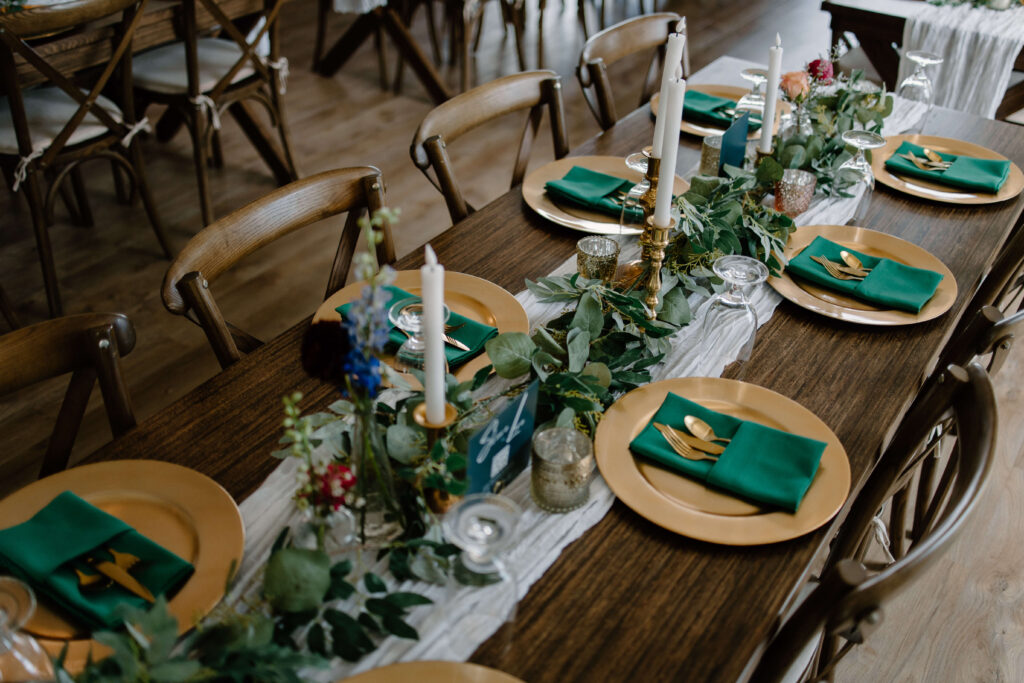 Wedding tablescape comprised of emerald green linens and beautiful wooden accents