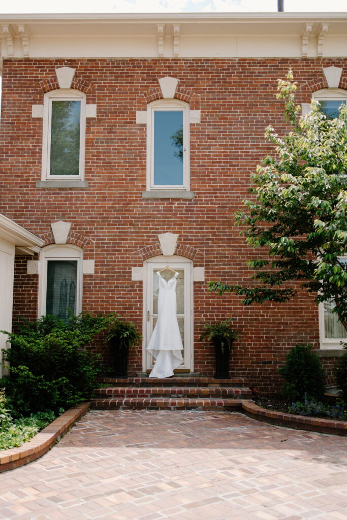 Bride's gown hangs in doorway of brick building