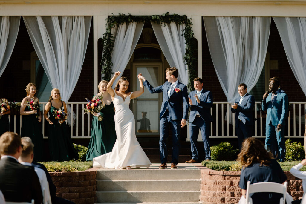 Documentary-style photographer captures bride dancing as she comes down the aisle while her groom looks on joyfully