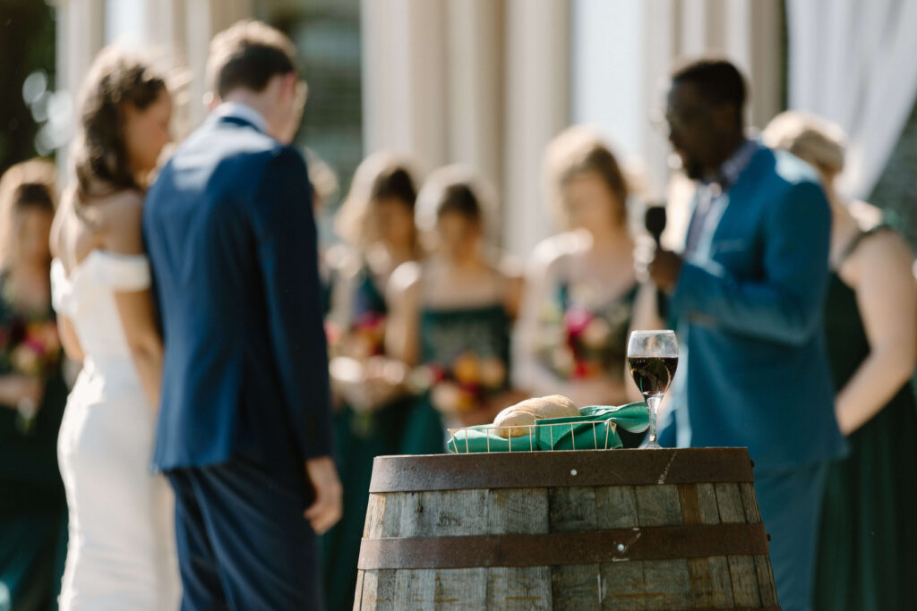 Bread and wine sits on vintage barrel as bride and groom pray together