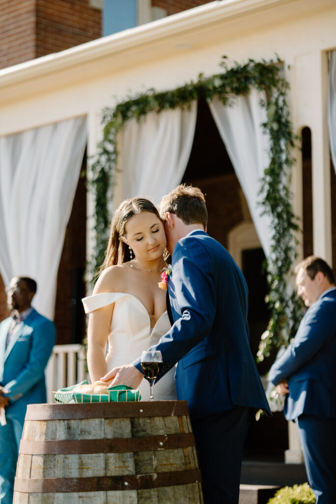 Groom hugs bride while breaking the bread for Holy Communion