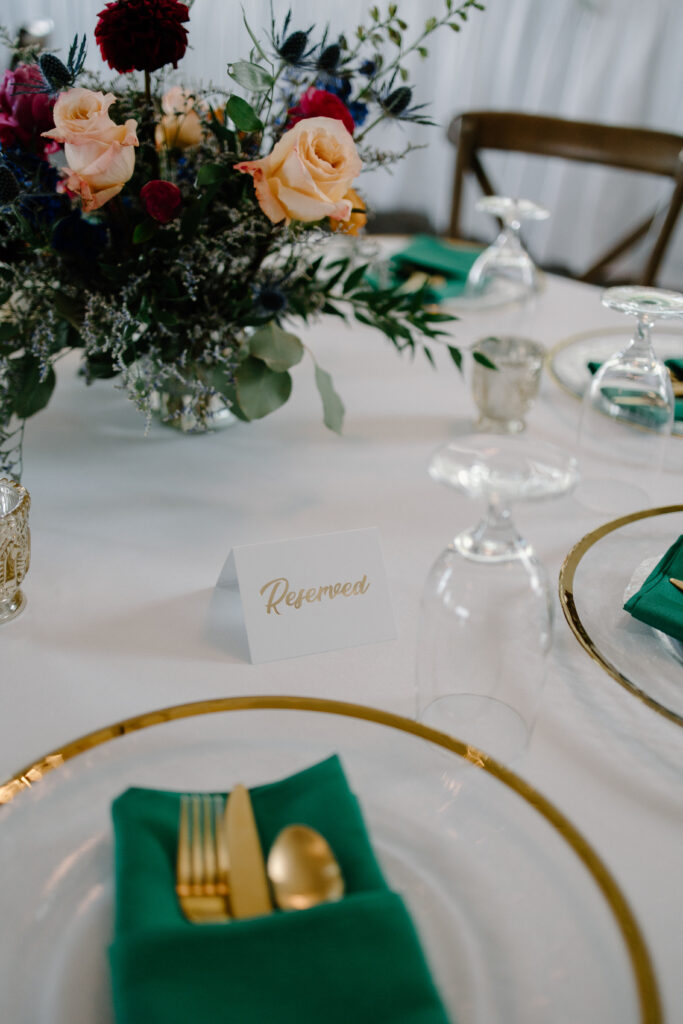 Emerald green linen napkins and bright roses on wedding day tablescape