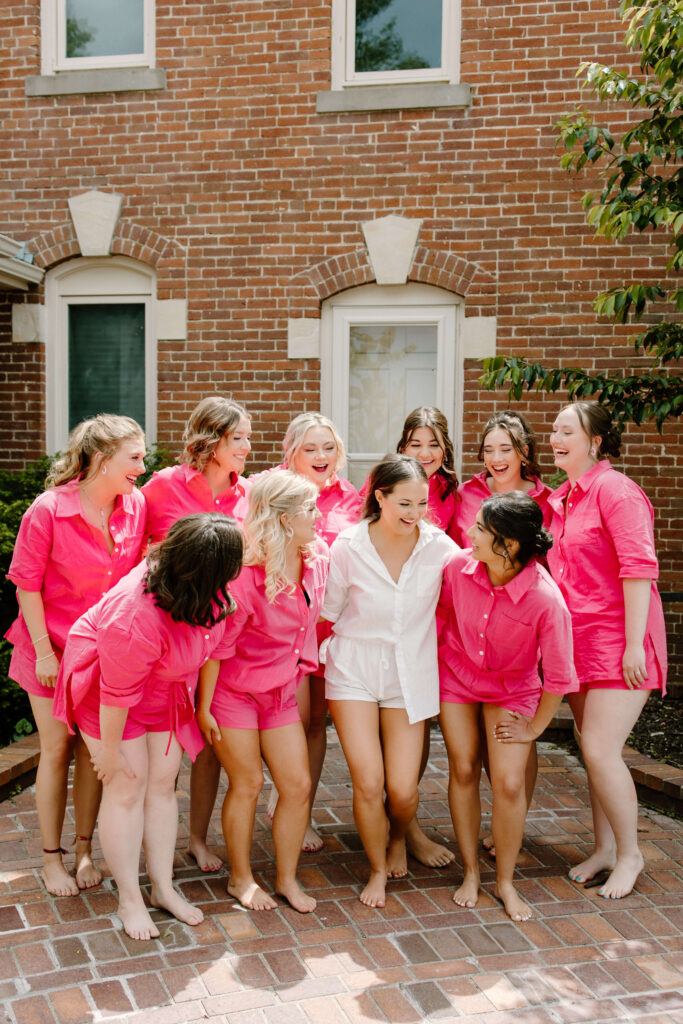 Bride and bridesmaids laugh in hot pink pajamas