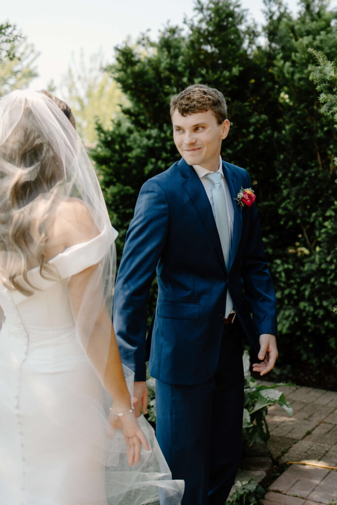 Groom looks back at bride during documentary-style first look