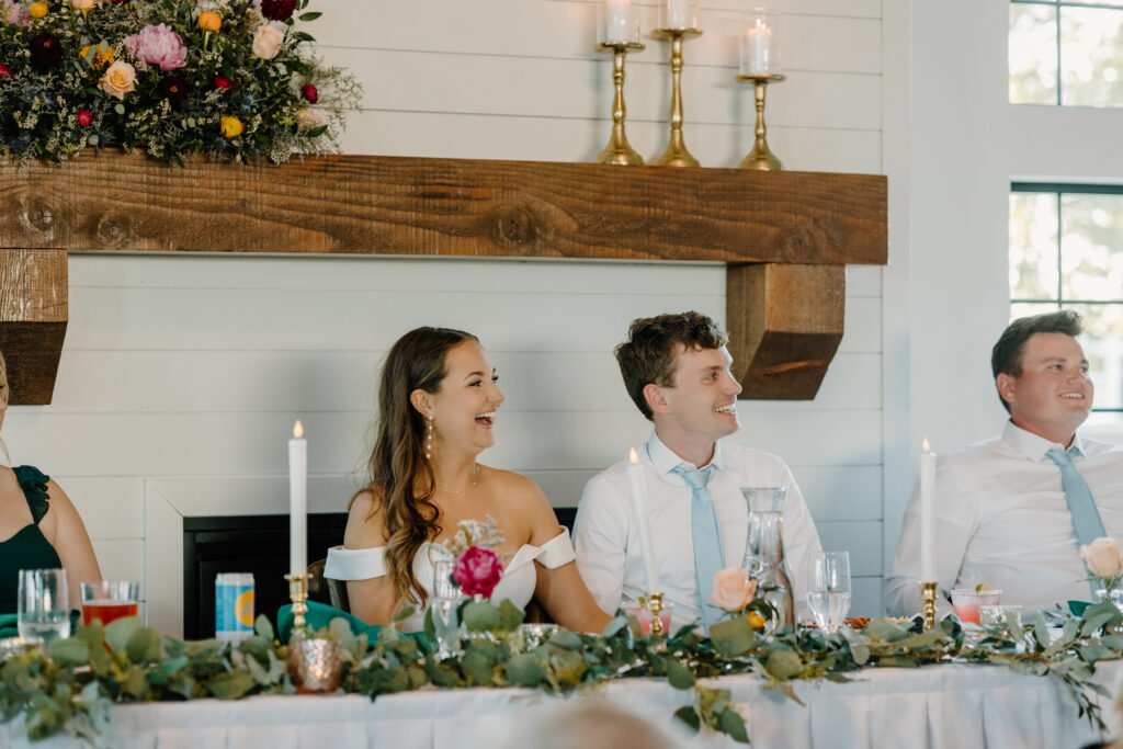 Documentary-style photographer captures candid photo of bride and groom smiling at a toast