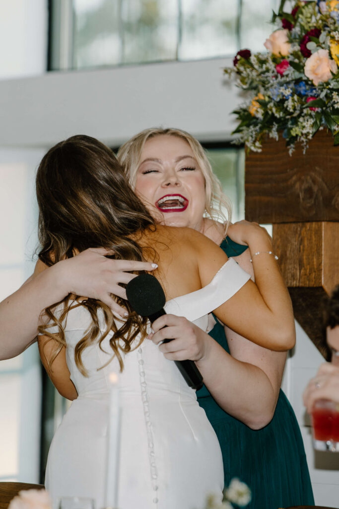 Maid of honor hugs bride as documentary-style photographer captures it