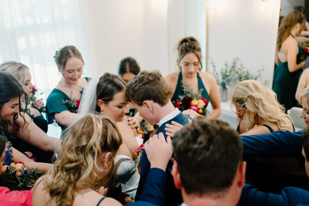 Bridal party prays over bride and groom before ceremony