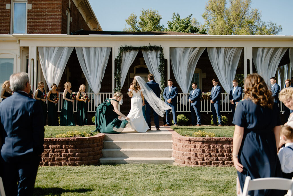 Wedding ceremony begins as maid of honor fixes bride's train before the couple exchanges vows