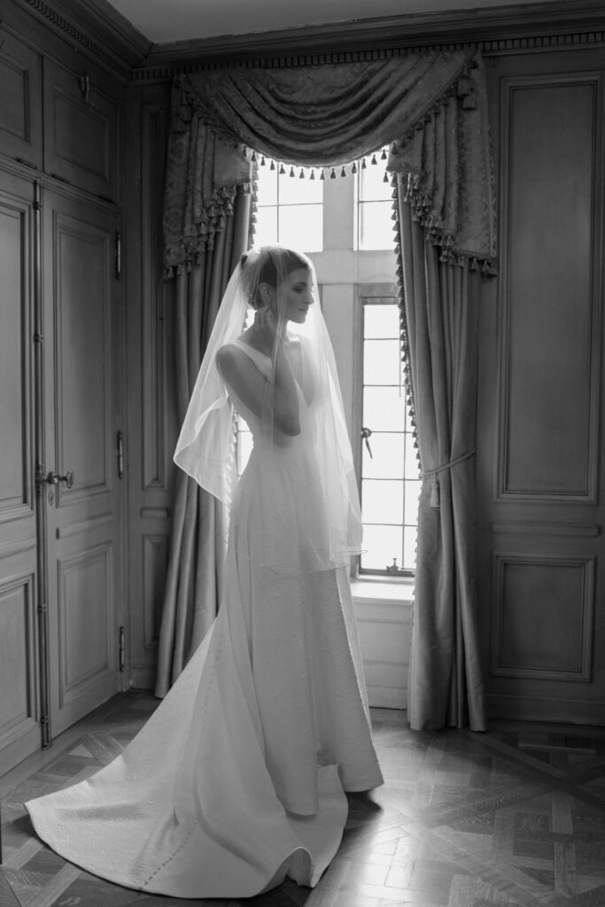 Bride with veil over her face cups her face