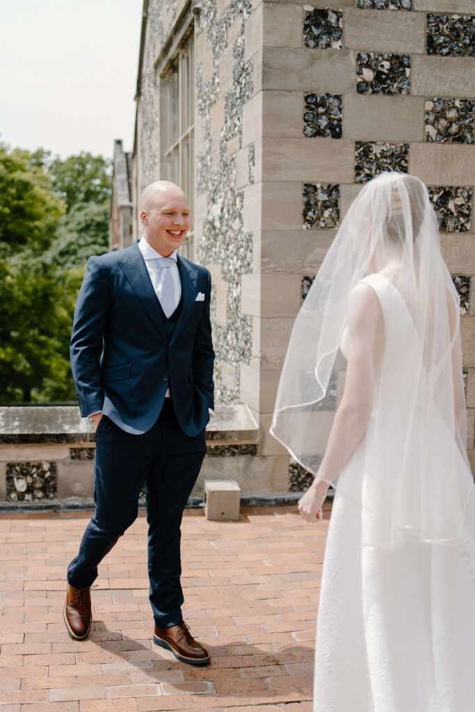 Groom smiles at his bride as he gets his first look on the balcony of Salisbury House