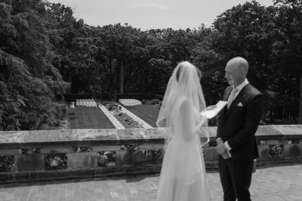 Bride and groom exchange vows on balcony overlooking garden wedding