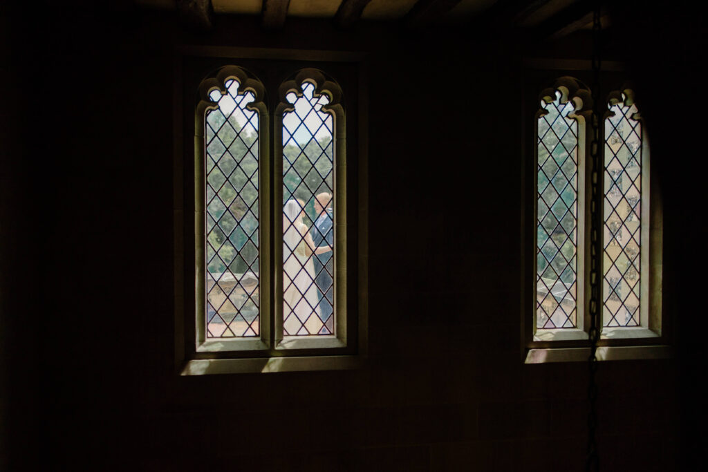 Bride and groom exchange their private vows at garden party through Gothic style windows