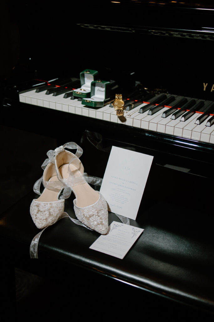 Couple's wedding day details sit on the bench and keys of a Yamaha piano in a hotel lobby