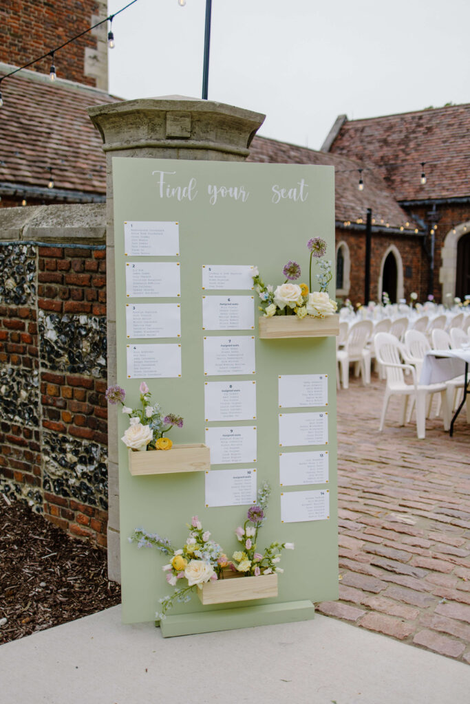 Creative seating chart adorned with flowers at garden wedding