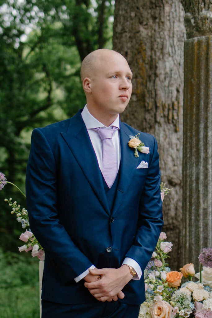 Groom tears up as bride comes down the aisle of garden wedding