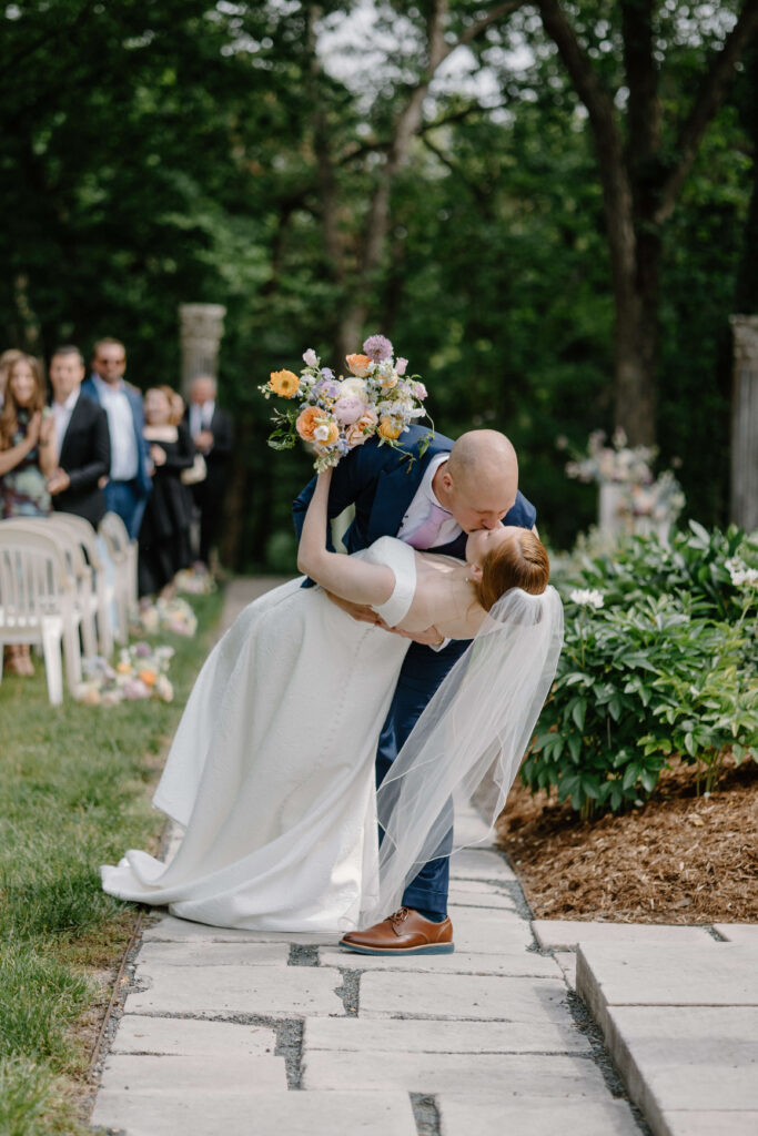 Groom dips bride to the ground as he kisses her for the first time as newlyweds