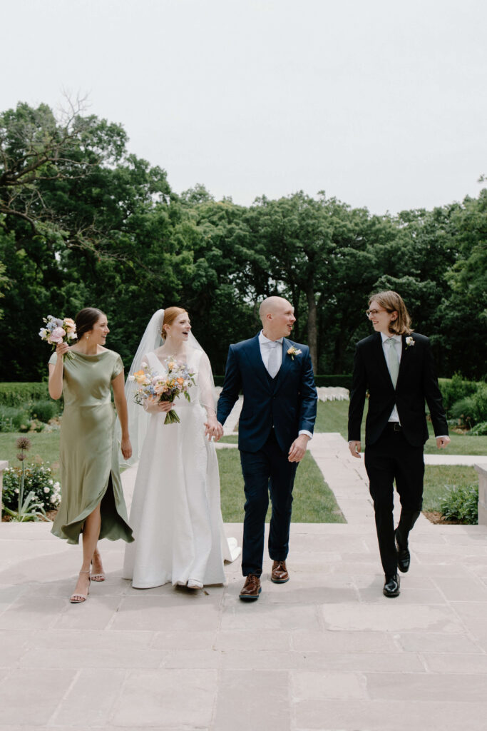 Small bridal party in intimate garden wedding laughs and walks together