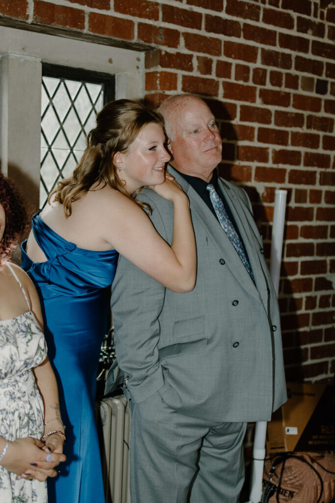 Sister of the groom and father of the groom watch the emotional first dance of the newlyweds