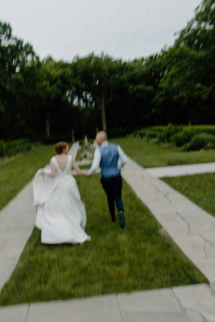 Bride and groom run through garden wedding